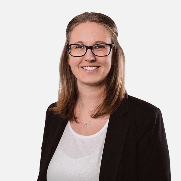 Porträt von Imke Backhaus, einer Frau mit schulterlangem braunem Haar und Brille, die in einem schwarzen Blazer und weißem Oberteil freundlich in die Kamera lächelt.