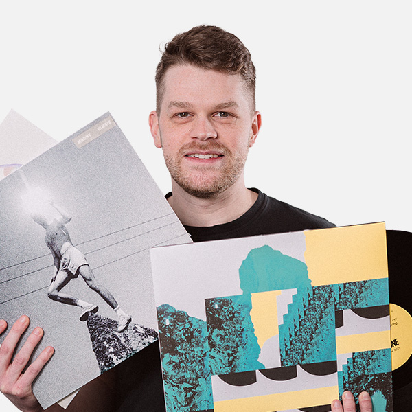 Maurice Schwarze hält mehrere Schallplatten mit farbenfrohen und künstlerischen Covern in den Händen und lächelt in die Kamera vor weißem Hintergrund.
