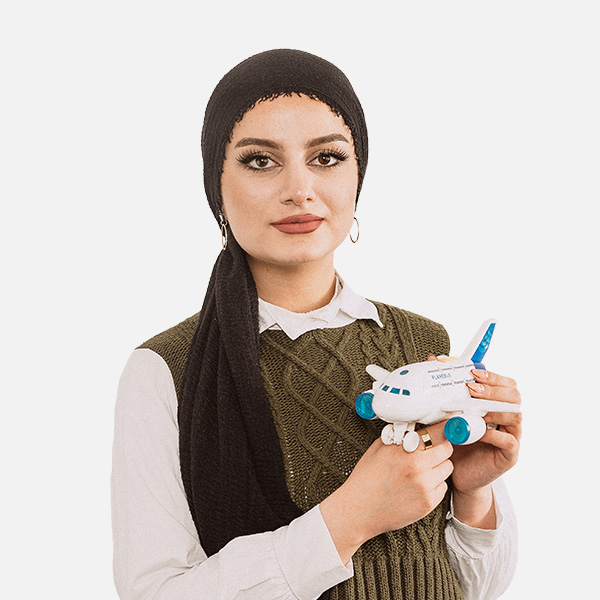 Shahed Hamo mit schwarzem Kopftuch hält ein Modellflugzeug vor weißem Hintergrund.