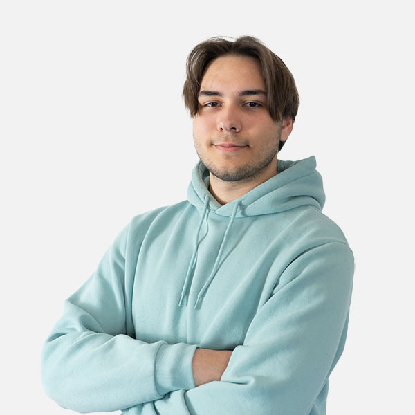 Tobias Hofmann mit verschränkten Armen in einem hellblauen Hoodie, strahlt Selbstbewusstsein und gelassen vor einem neutralen Hintergrund aus.