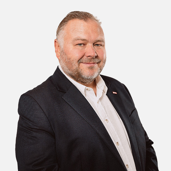 Porträt von Peter Embscher, Geschäftsführer, in dunklem Anzug und weißem Hemd vor neutralem Hintergrund.