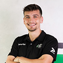 Porträt von Jonas Libor in einem schwarzen Hannover-96-Poloshirt mit verschränkten Armen und freundlichem Lächeln.