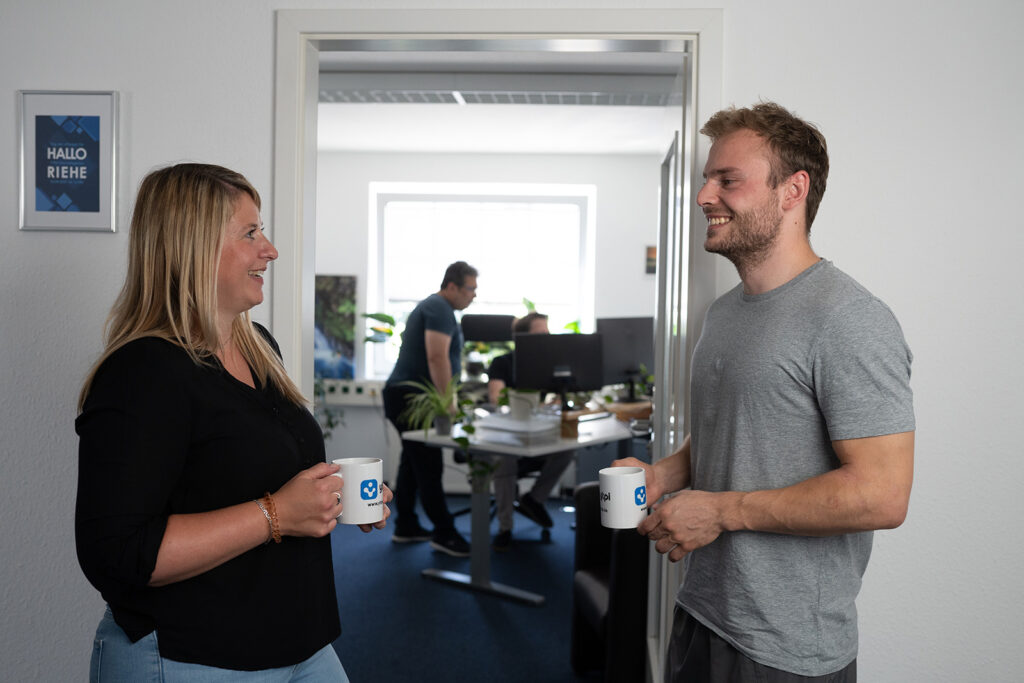 Zwei Kolleg:innen bei der Kaffeepause im Büro der Agentur YTPI im freundlichen Austausch.