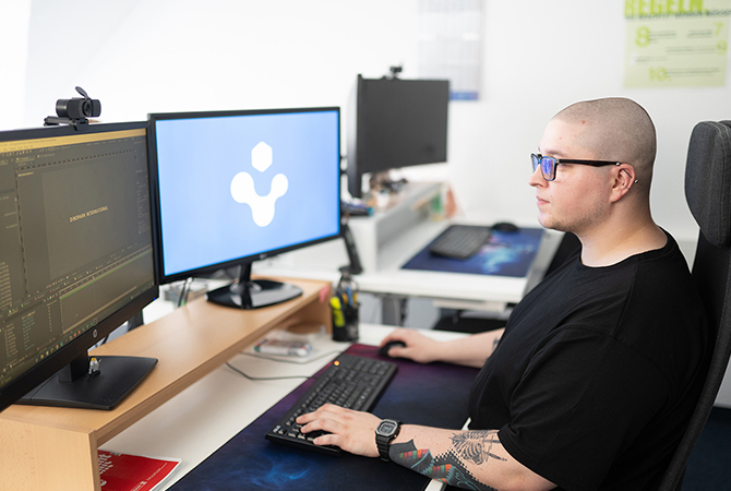 YTPI Webdesigner bearbeitet ein Video an zwei Monitoren in einem modernen Büro.