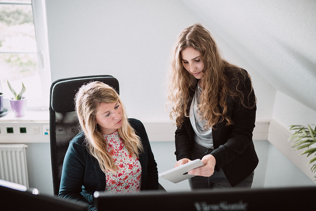 Zwei Frauen im Büro besprechen gemeinsam Inhalte im Online-Marketing auf einem Tablet.
