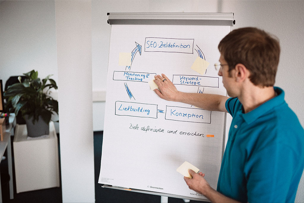 Online Marketing Mitarbeite erklärt SEO-Strategie und Kampagnenplanung am Flipchart – Keyword-Strategie, Linkbuilding und Zieldefinition