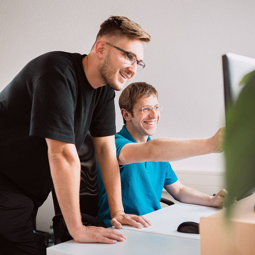 Zwei Mitarbeiter bei YTPI, die gemeinsam am PC arbeiten.