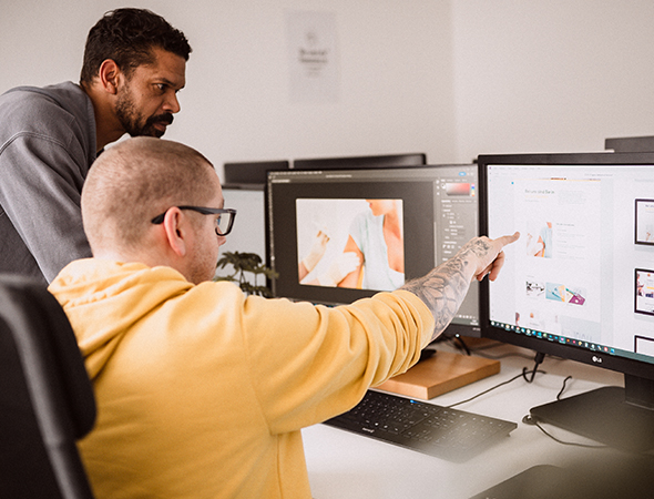 Grafiker und Webdesigner besprechen am Bildschirm Layouts und Designideen für eine Website