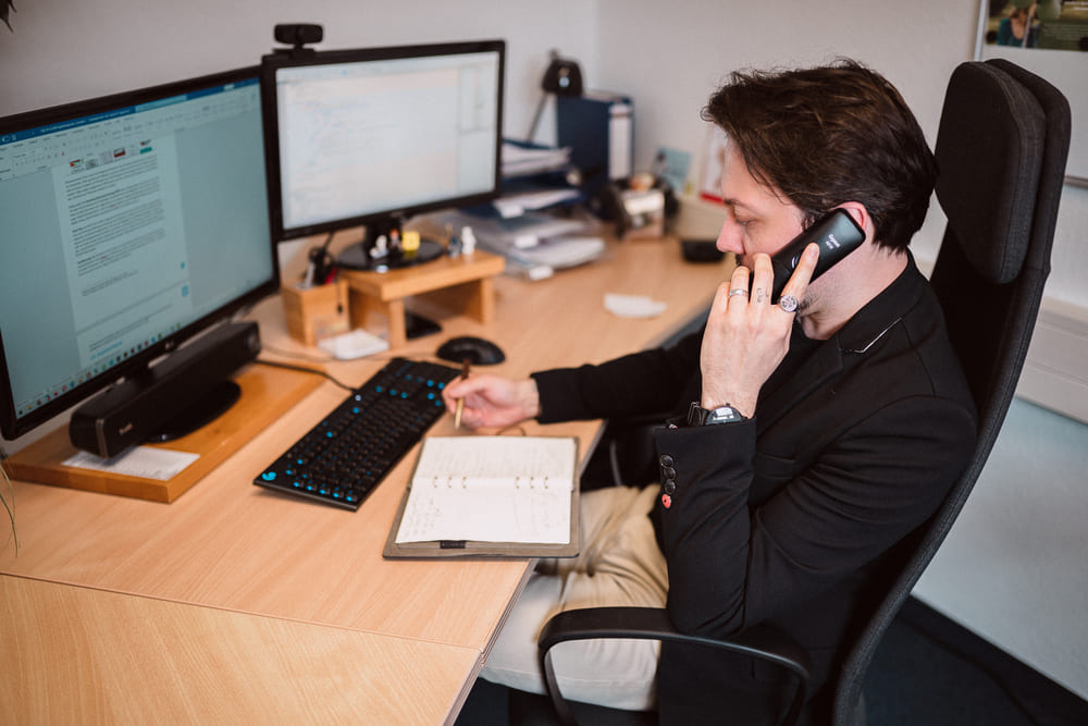 Vertriebsmitarbeiter im Gespräch mit Kunden am Telefon – Planung, Beratung und Koordination von digitalen Projekten am Arbeitsplatz